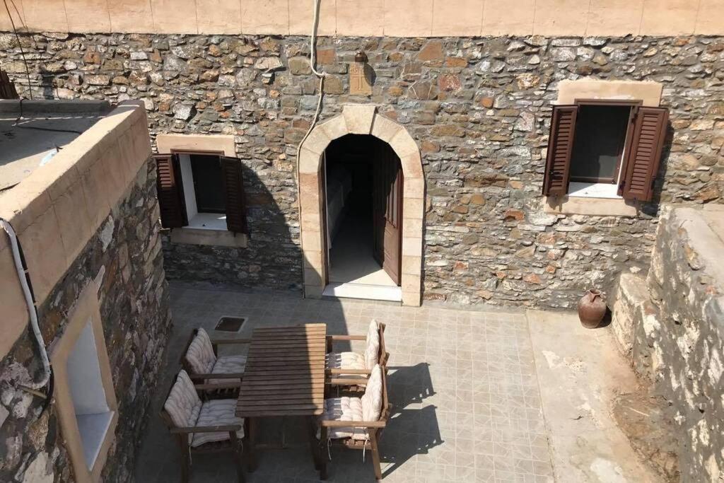 AsklipiḯonYiannis Village house的一个带椅子的庭院和一座带门廊的石头建筑