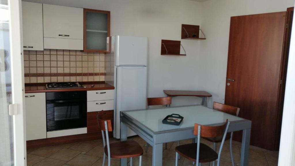丽都玛里尼SPELU - Appartamento con terrazza fronte mare的厨房配有桌椅和冰箱。