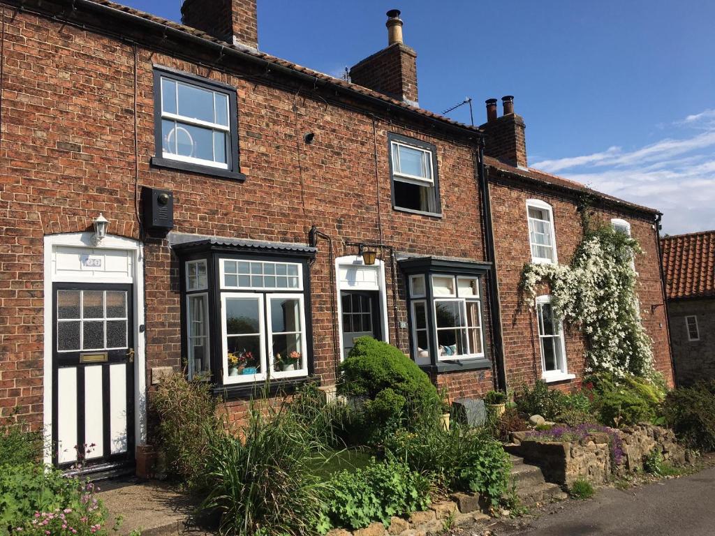 TealbyCosy Lincs Wolds cottage in picturesque Tealby的红砖房子,设有黑白窗户
