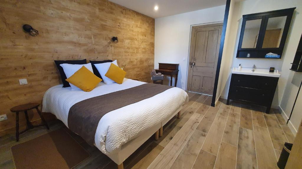 ÉpoyeL'Hébergerie的一间卧室设有一张大床和木墙