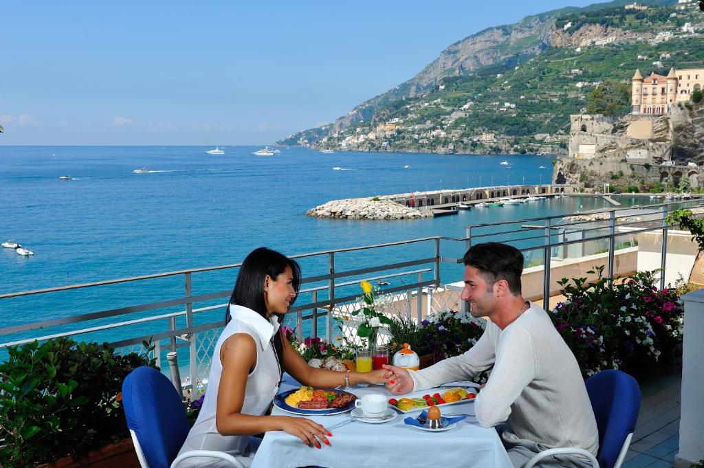 马奥莱全景酒店的坐在桌子上的男人和女人,欣赏海洋
