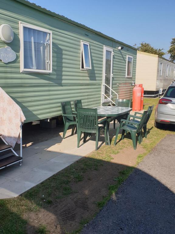 波斯考尔Inviting 3-Bed Caravan in Porthcawl的绿色大篷车前的野餐桌和椅子