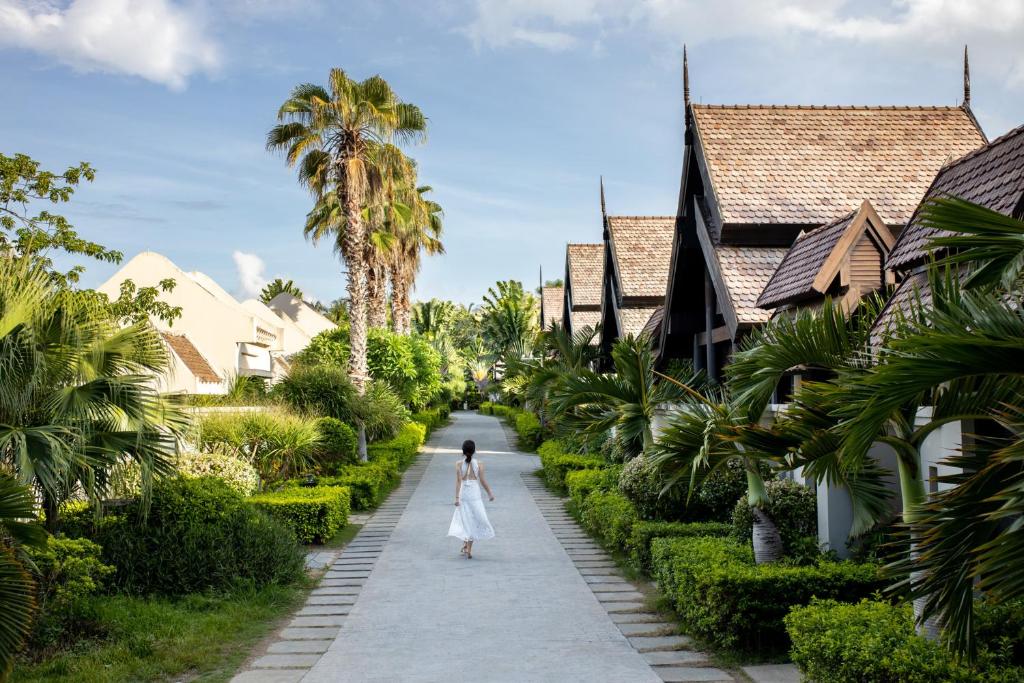 三亚三亚亚龙湾铂尔曼别墅度假酒店(免税城95折+旅拍)的穿白色衣服的女人在房子之间走着一条小径