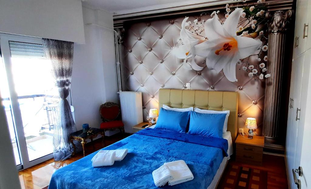 比雷埃夫斯LUXURY APARTMENT 6 PEOPLE PORT OF PIRAEUS的卧室配有一张蓝色的床,墙上挂着鲜花
