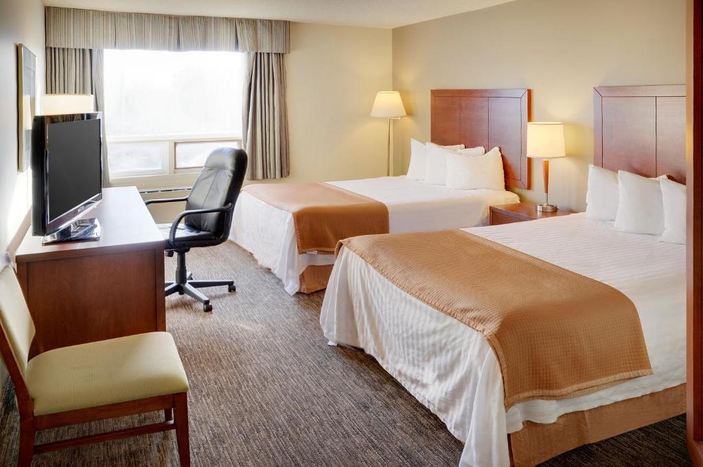 北湾Quality Inn的酒店客房设有两张床、一张桌子和一台电视。
