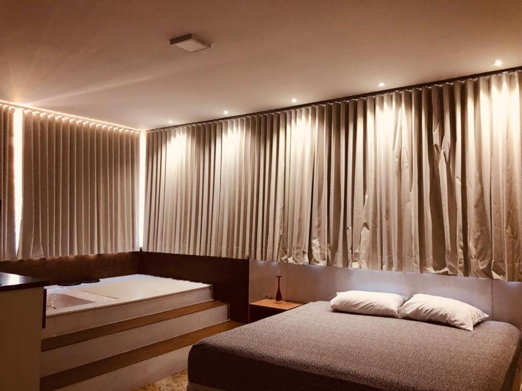 波苏斯-迪卡尔达斯Hotel Pousada Beija Flor的卧室配有两张床,位于窗帘前
