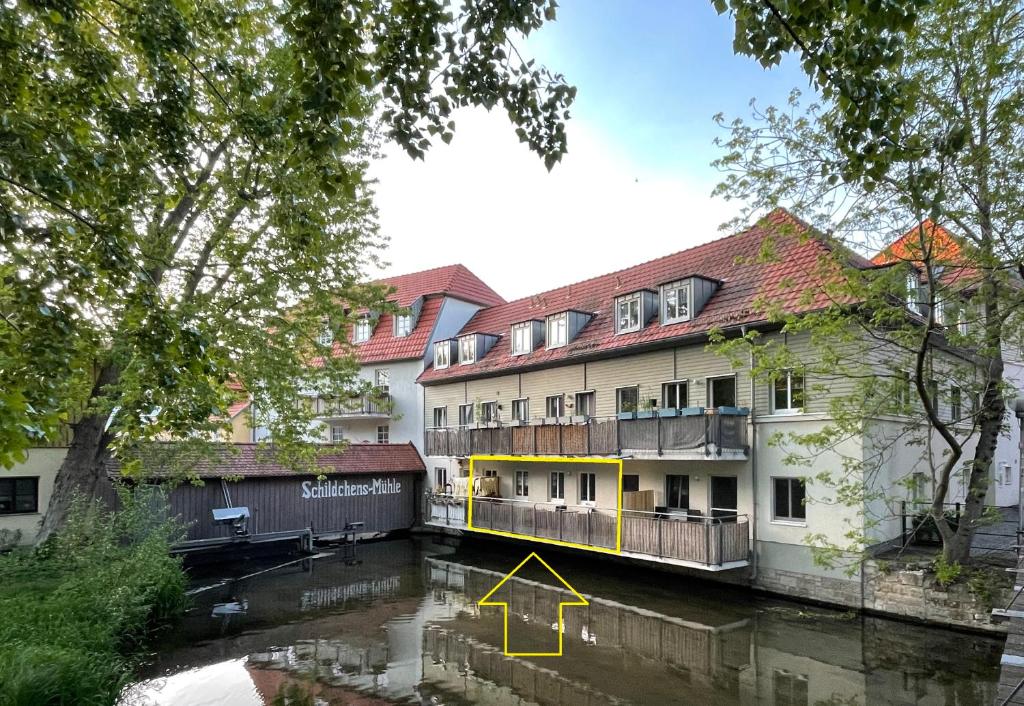 爱尔福特Ferienwohnung Blickfang - Modernes Apartment direkt in der Altstadt von Erfurt mit Balkon - beste Lage und Aussicht的一条黄箭头指向河边的建筑物