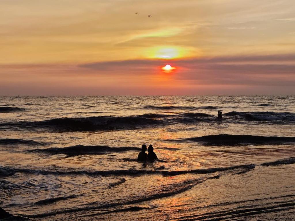 伊斯塔帕普拉亚琳达宾馆的日落时分,两人坐在海滩的水面上
