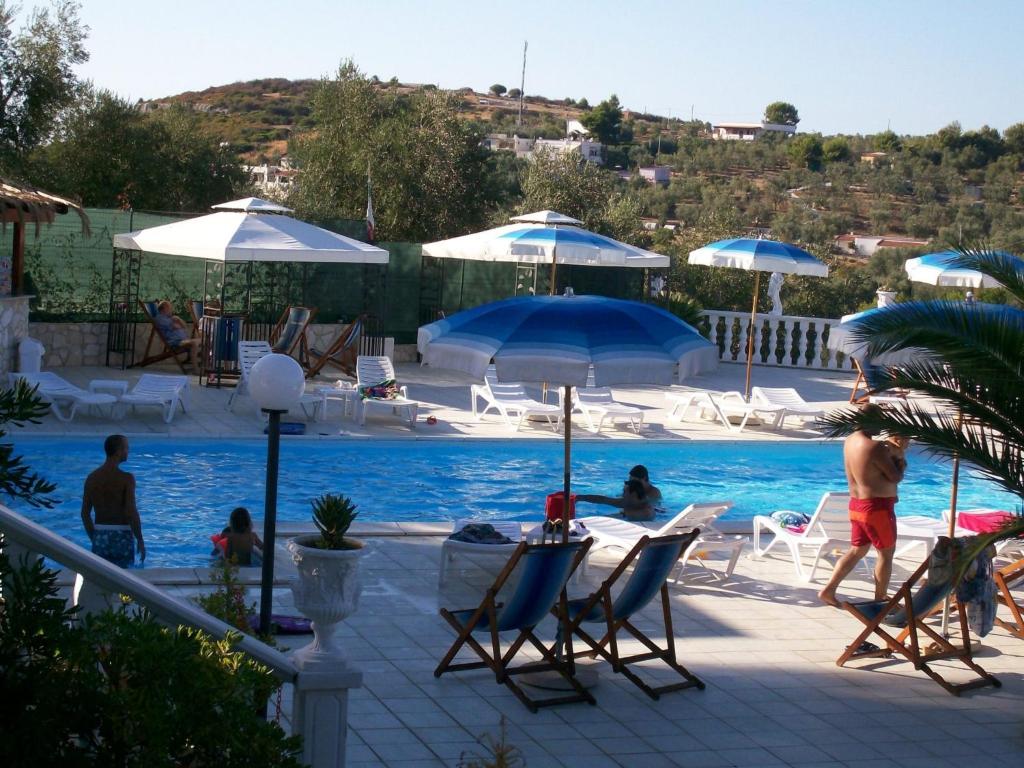 维耶斯泰阿尔泰雅乡村公寓酒店的游泳池配有椅子和遮阳伞,周围的人可以坐在游泳池周围