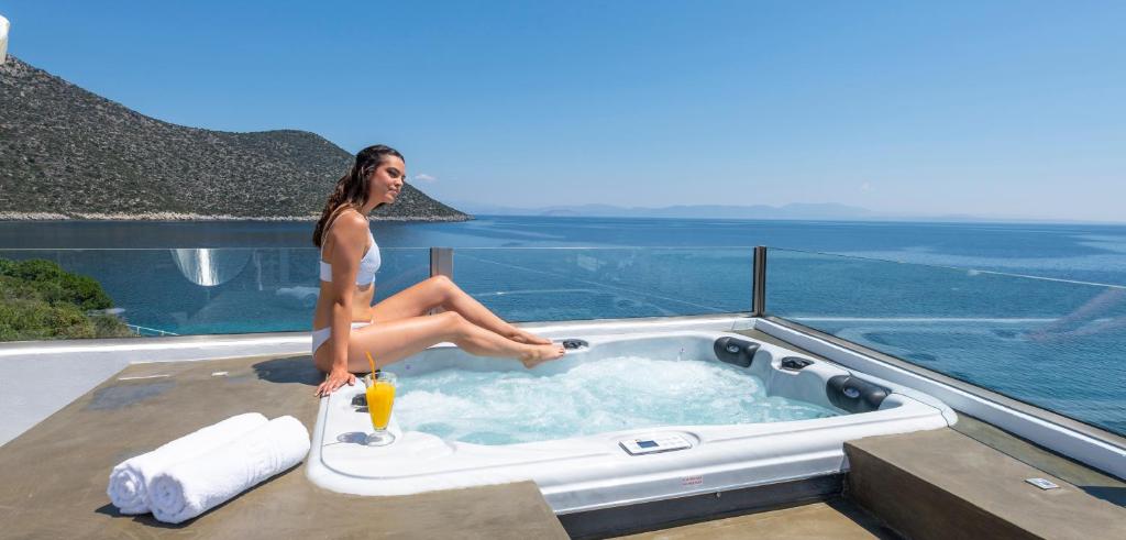 蒂洛斯Paraskevas Boutique Hotel的坐在热水浴缸中的女人,坐在房子的顶部