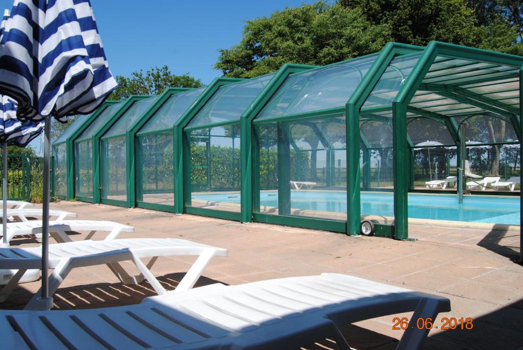 Moidrey曼德黑湾度假酒店的一个带椅子和遮阳伞的绿色结构的游泳池
