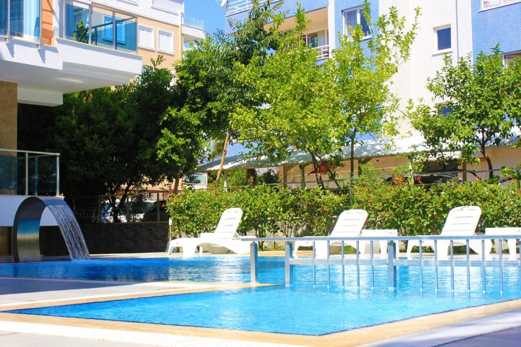 安塔利亚Alfa Apart Hotel的一个带白色椅子的游泳池和一个喷泉