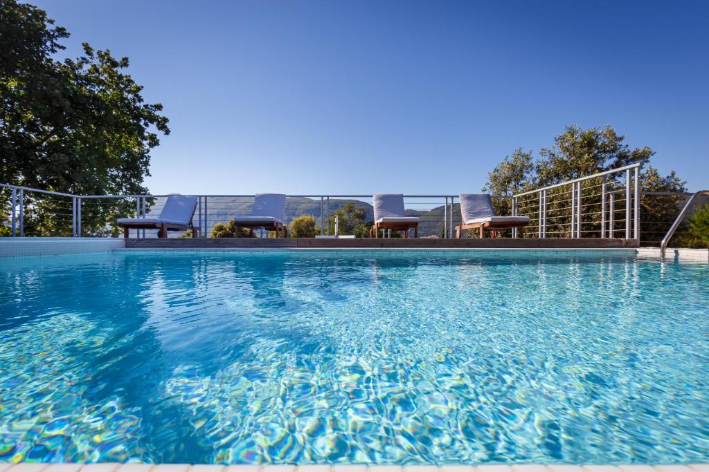 卡托克拉克阿纳Villa Dafni & Nikos Corfu的一座蓝色海水和椅子的大型游泳池