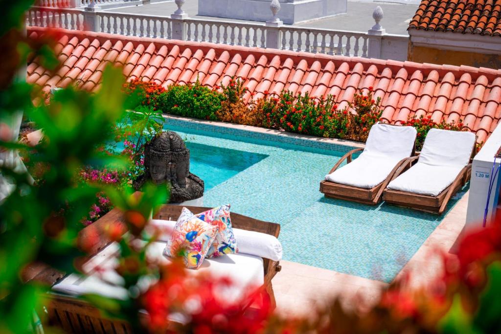 卡塔赫纳阿瓜马林纳精品酒店的一个带2把躺椅和雕像的游泳池