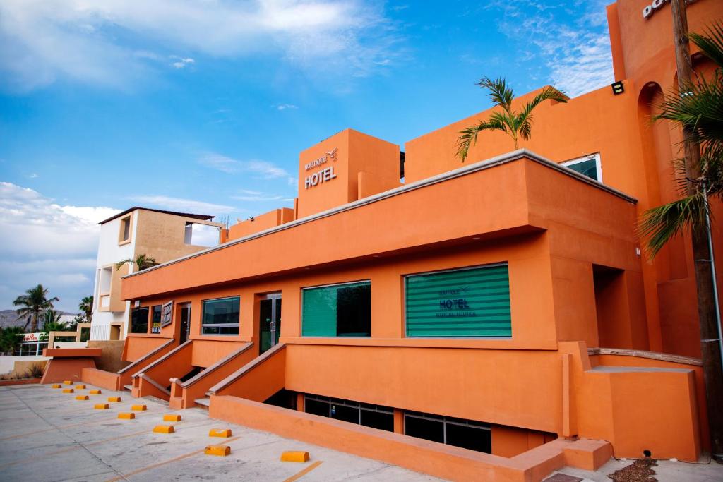 圣何塞德尔卡沃Hotel Boutique Plaza Doradas的一座种植了棕榈树的橙色建筑