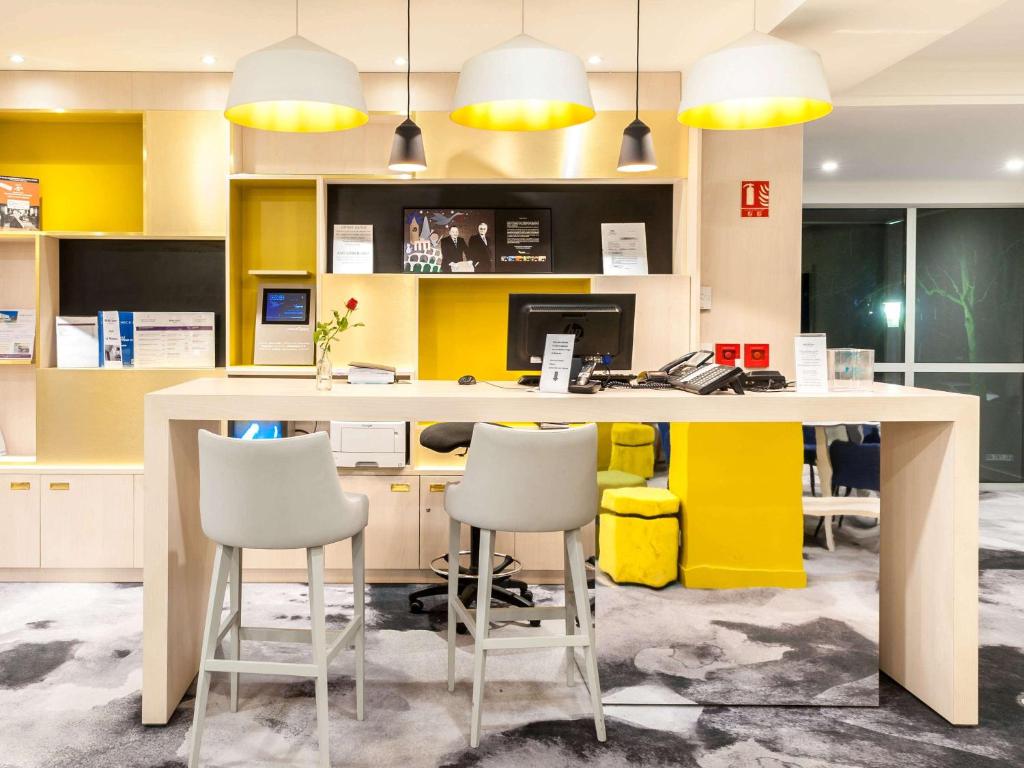 马孔Hôtel Mercure Mâcon Bord de Saône的办公室设有黄色和白色的桌子和椅子