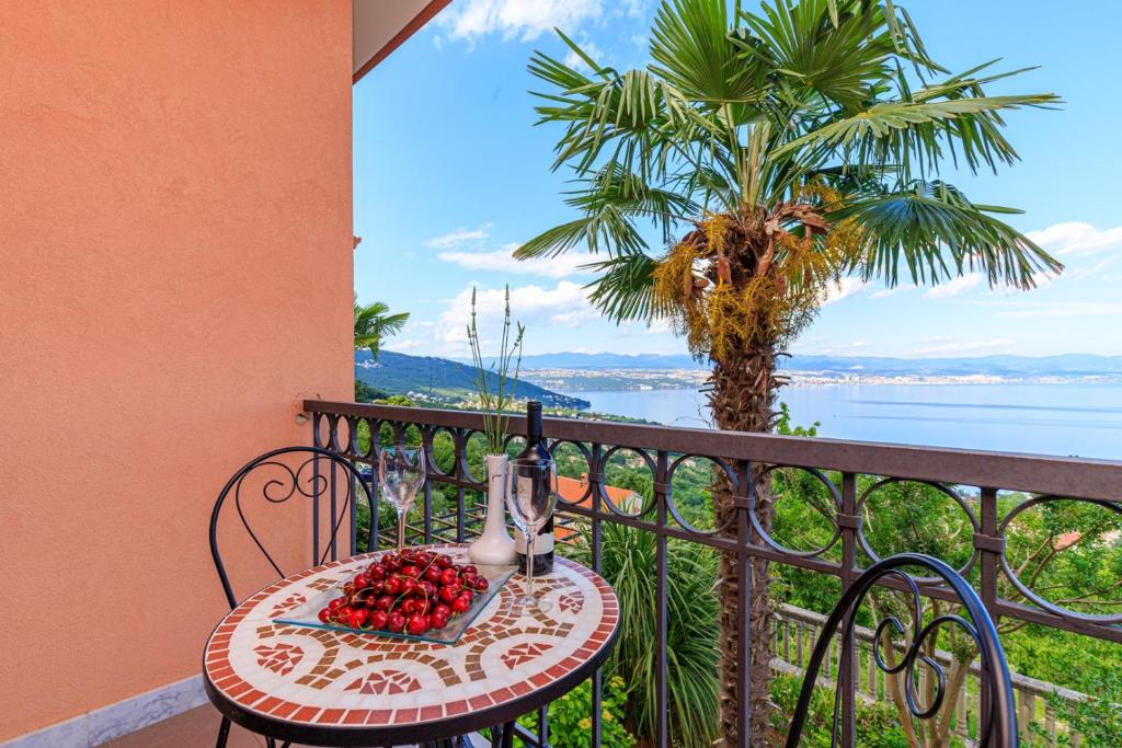 洛夫兰Apartments Jasminka Lovran的棕榈树阳台的水果桌