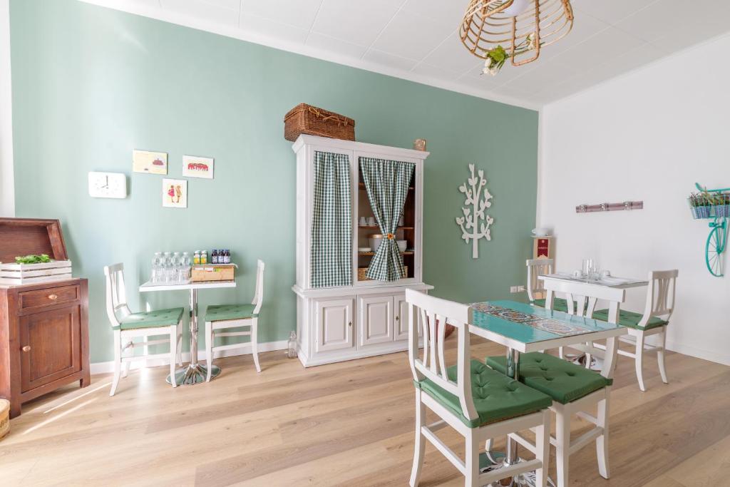 福利尼奥Dama Bed & Breakfast的一间拥有绿色墙壁和桌椅的用餐室