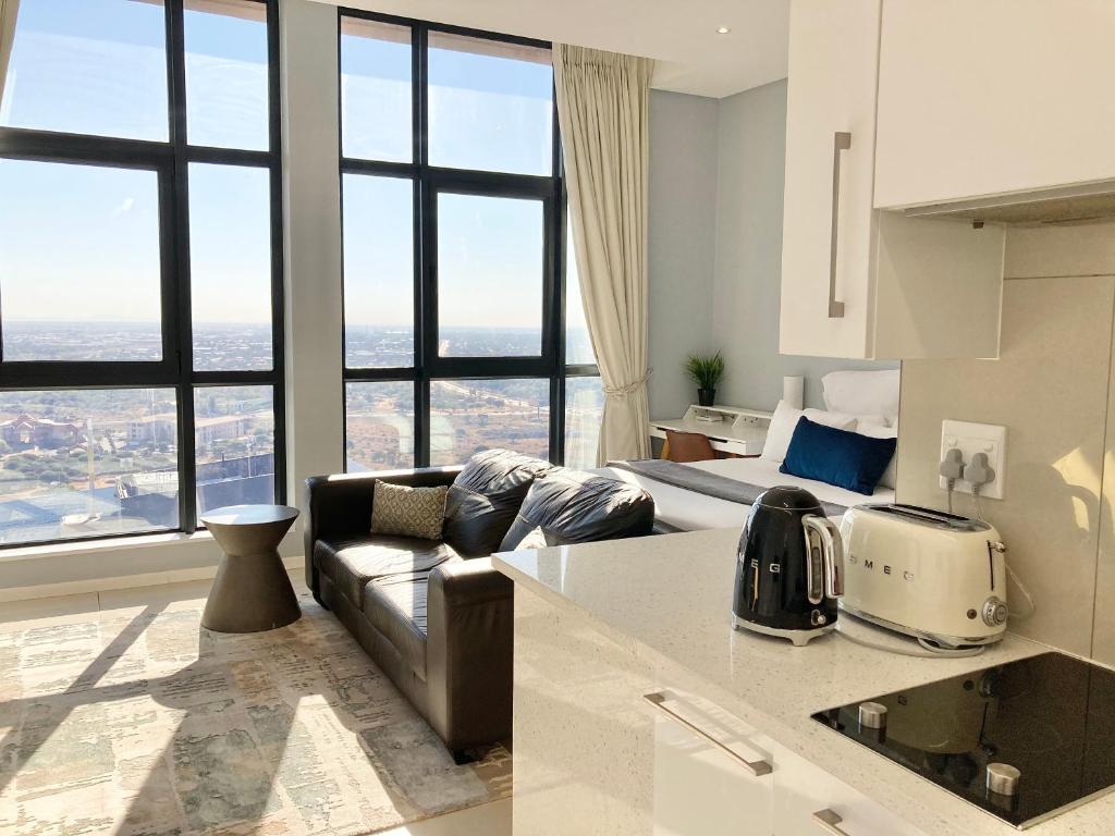 哈博罗内Urban Awe Apartment-iTowers 23rd Floor的带沙发的客厅和带窗户的厨房