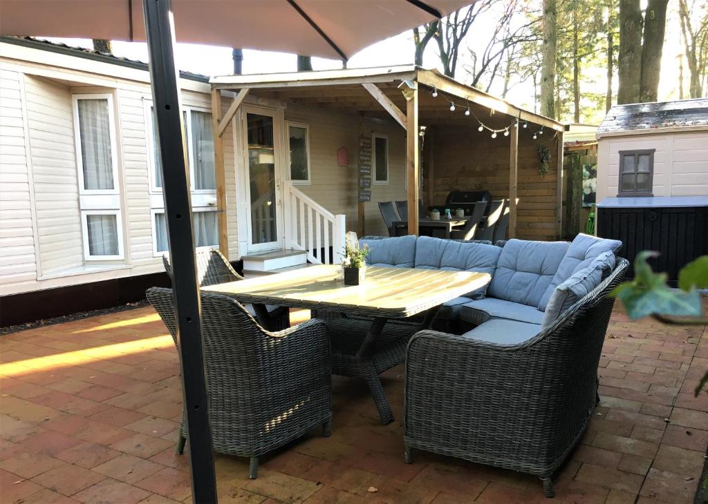 洪德洛Prachtige Luxe chalet op de Veluwe nabij Hoenderloo的庭院配有桌椅和遮阳伞。