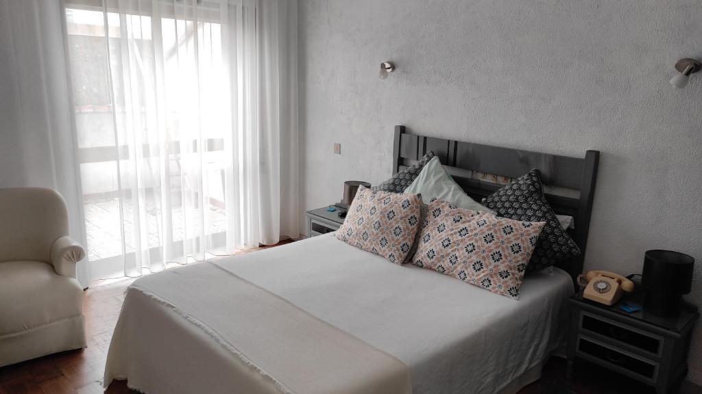 布拉加Terrace House的卧室配有带枕头的白色床和窗户。