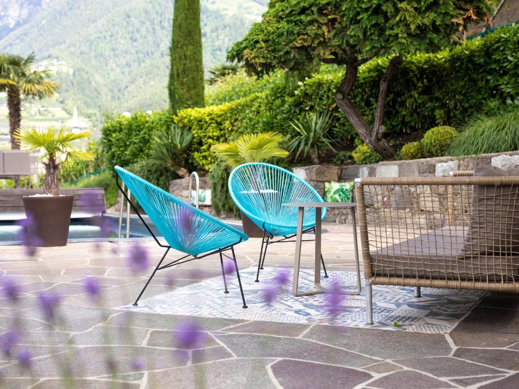 思科纳韦恩古特因内莱特霍夫酒店的三个蓝色椅子坐在一个种有紫色花卉的庭院里