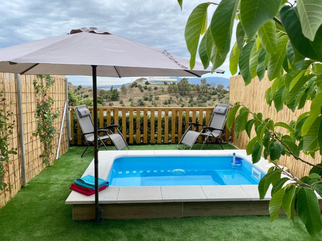 马拉加Suite Apto de Invitados- Heated Pool-Piscina Climatizada- Montes de Málaga的一个带遮阳伞和两把椅子及一张桌子的游泳池