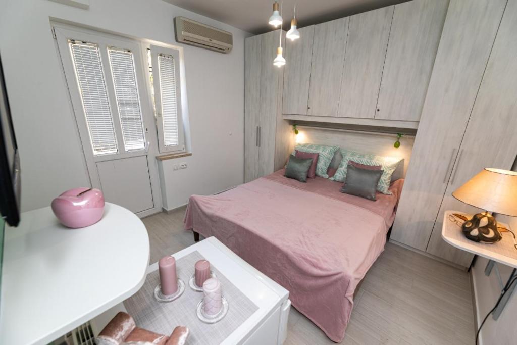 希洛Room Gržetić的一间小卧室,配有粉红色的床和一张桌子