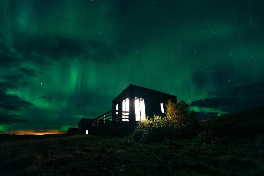 海拉Afternoon Cottages的夜间在北极光下的一个小屋