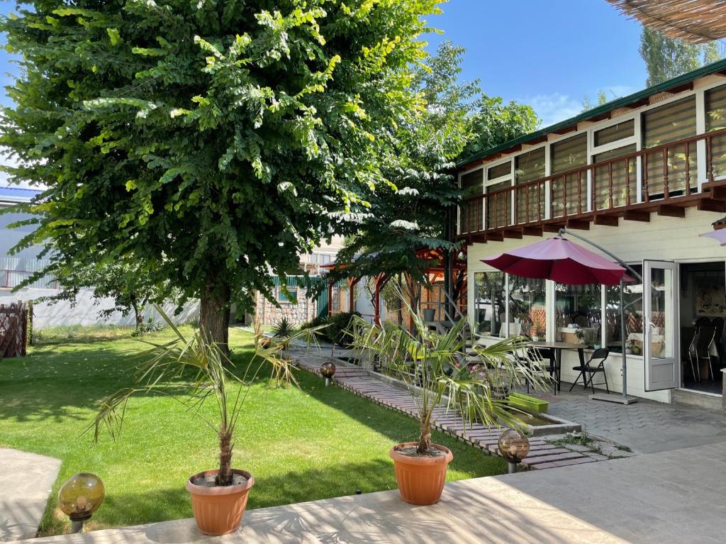 奥什生态之家旅馆的一个带树的庭院和一个带雨伞的桌子