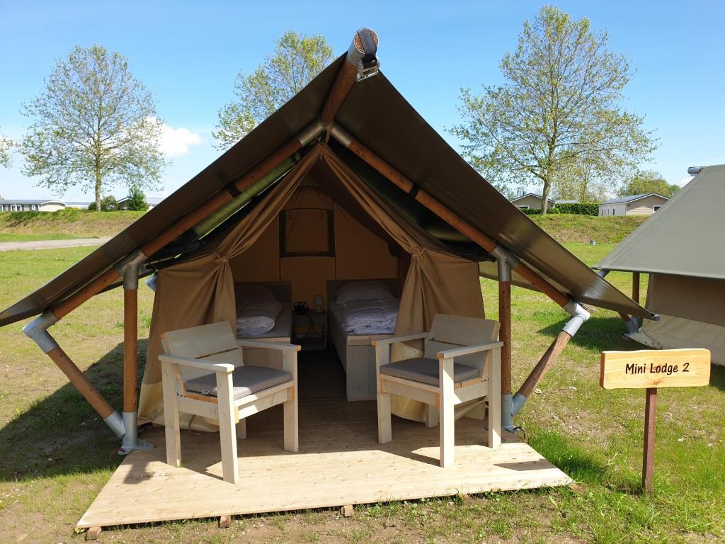 KesterenSafaritent Mini Lodge的配有两把椅子、一张桌子和一个标志的帐篷