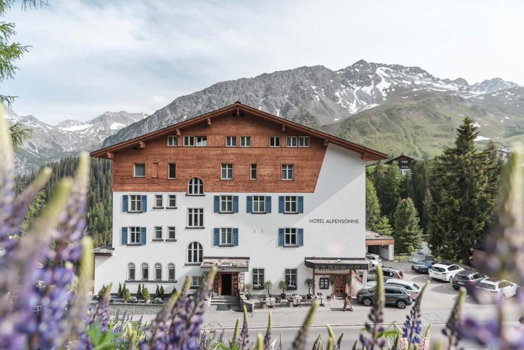 阿罗萨Hotel Alpensonne - Panoramazimmer & Restaurant的一座大建筑,背景是群山