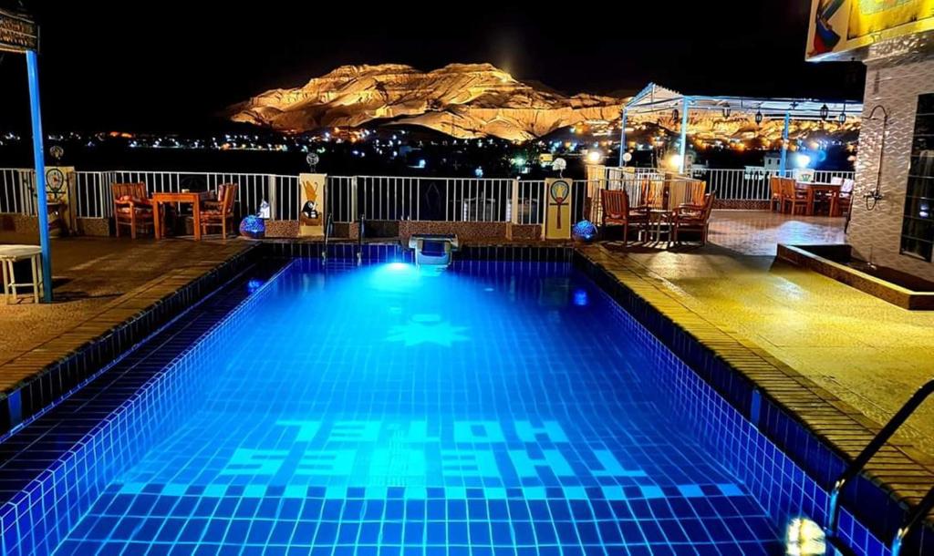 卢克索Thebes Hotel的一座晚上的游泳池,背景是一座山