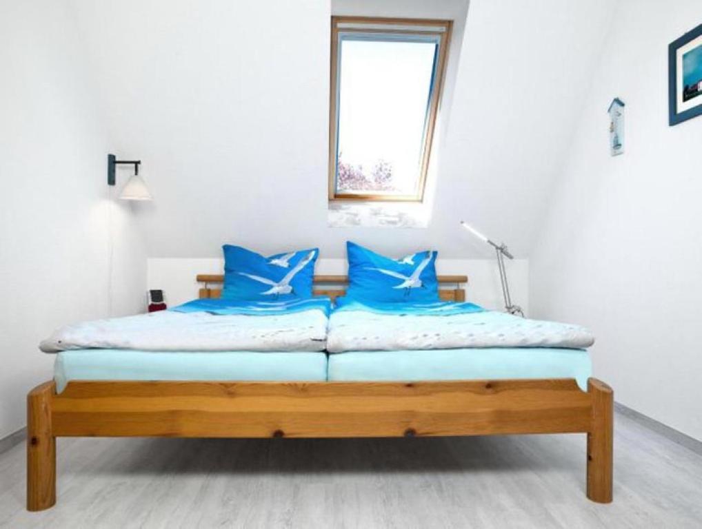 因塞尔波埃尔Wolkenlos的白色客房内的一张带蓝色枕头的床