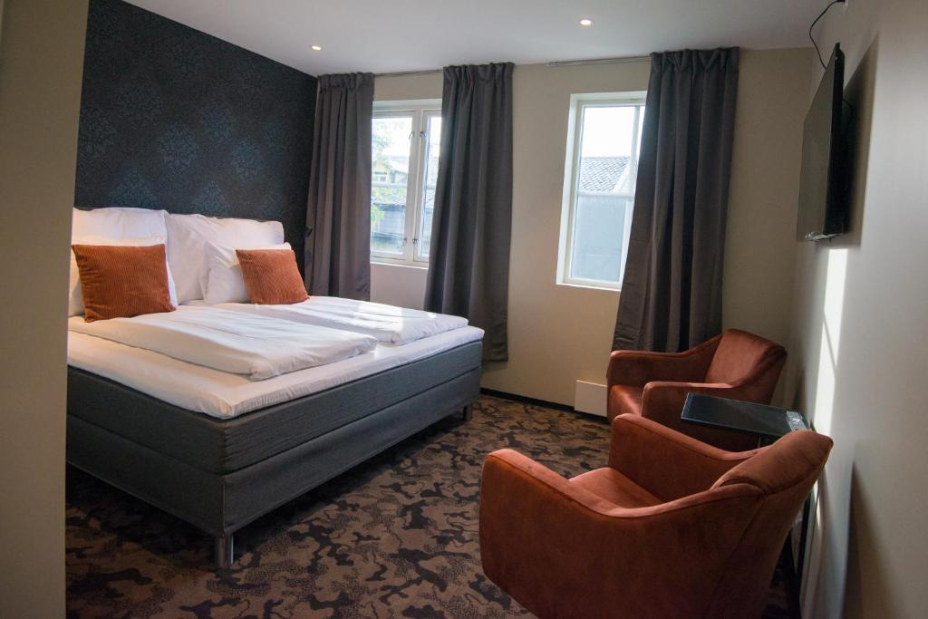 桑内舍恩Sandnessjøen Overnatting的酒店客房,配有一张床和两把椅子
