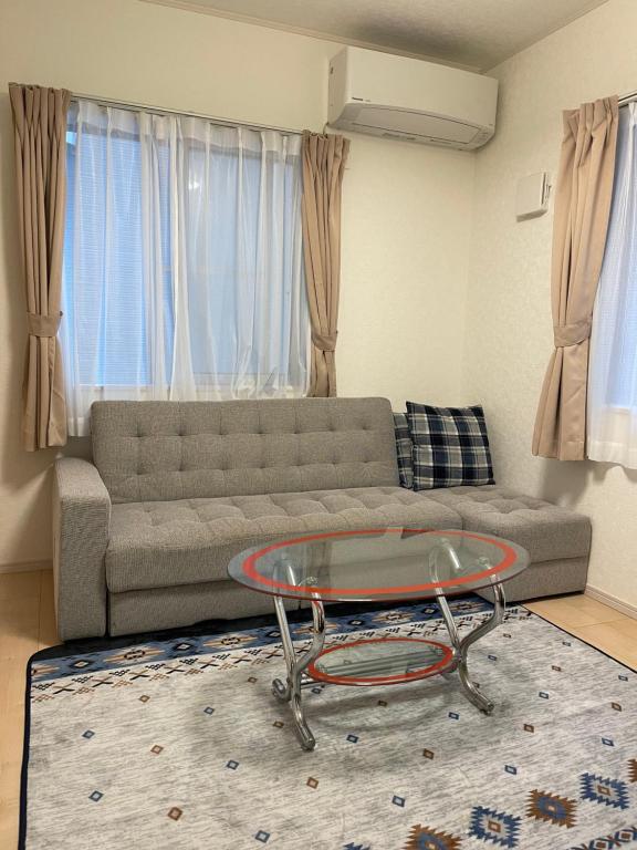 东京Bessalov Home 2nd room friendly house的带沙发和玻璃桌的客厅