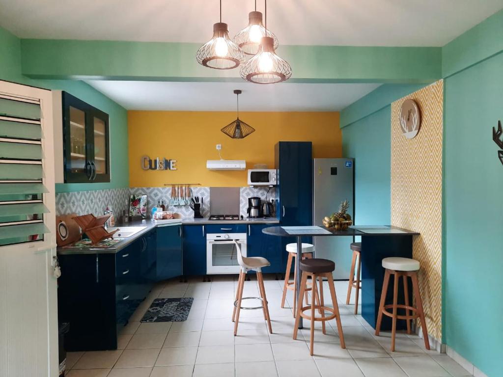 Rivière-PiloteVilla Casa Ti Choul的厨房拥有蓝色和黄色的墙壁和酒吧凳子