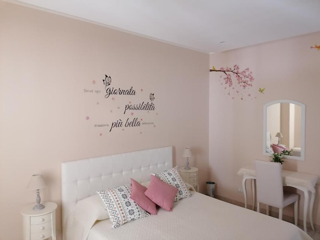 普尔萨诺La Casetta di Tiziana的卧室配有白色床和粉红色枕头