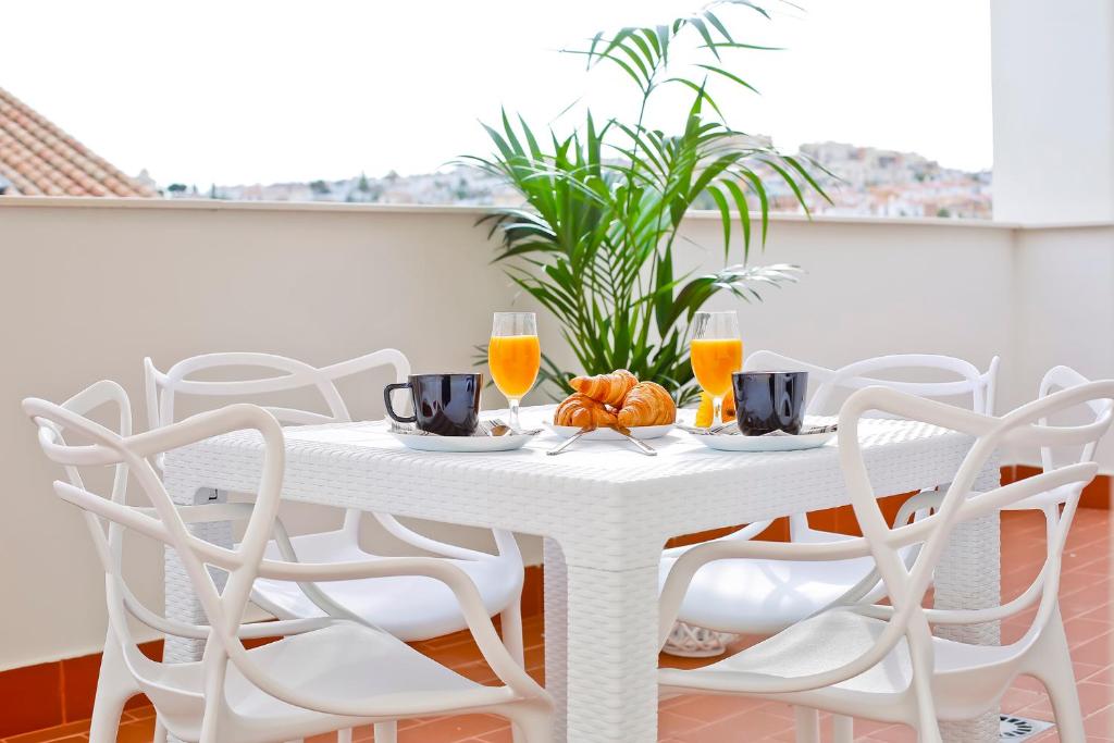 托雷德尔马尔Apartamentos Rincón del Mar的白色餐桌、白色椅子和橙汁