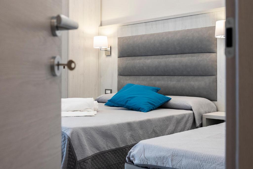 利多迪卡马约雷Versilia Residence - Colombo的客房设有两张床和蓝色枕头。