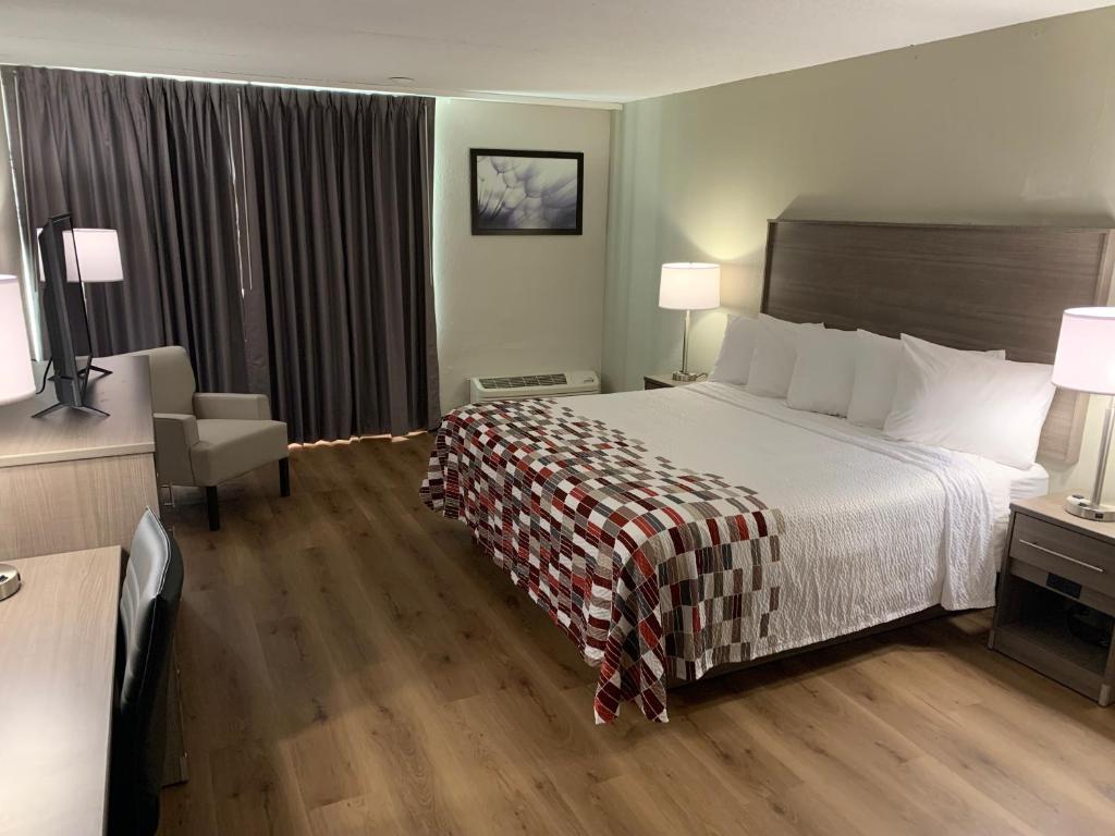尼亚加拉瀑布Red Roof Inn Niagara Falls的酒店客房带一张大床和一把椅子