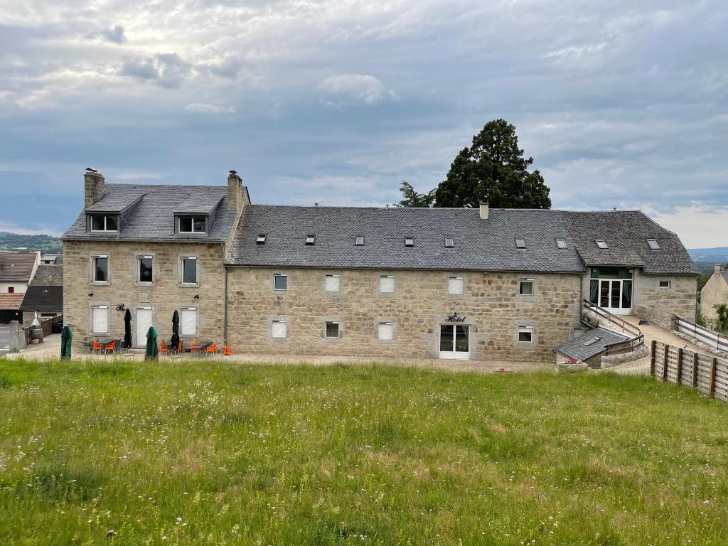 奥蒙奥布拉克La ferme de l'Aubrac的前面有草地的大型砖砌建筑