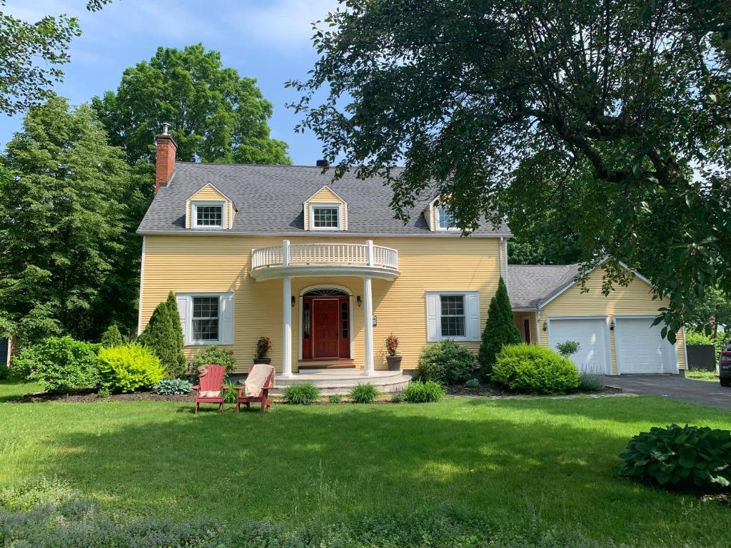 CowansvilleManoir Alegria的院子里的黄色房子,带两把椅子