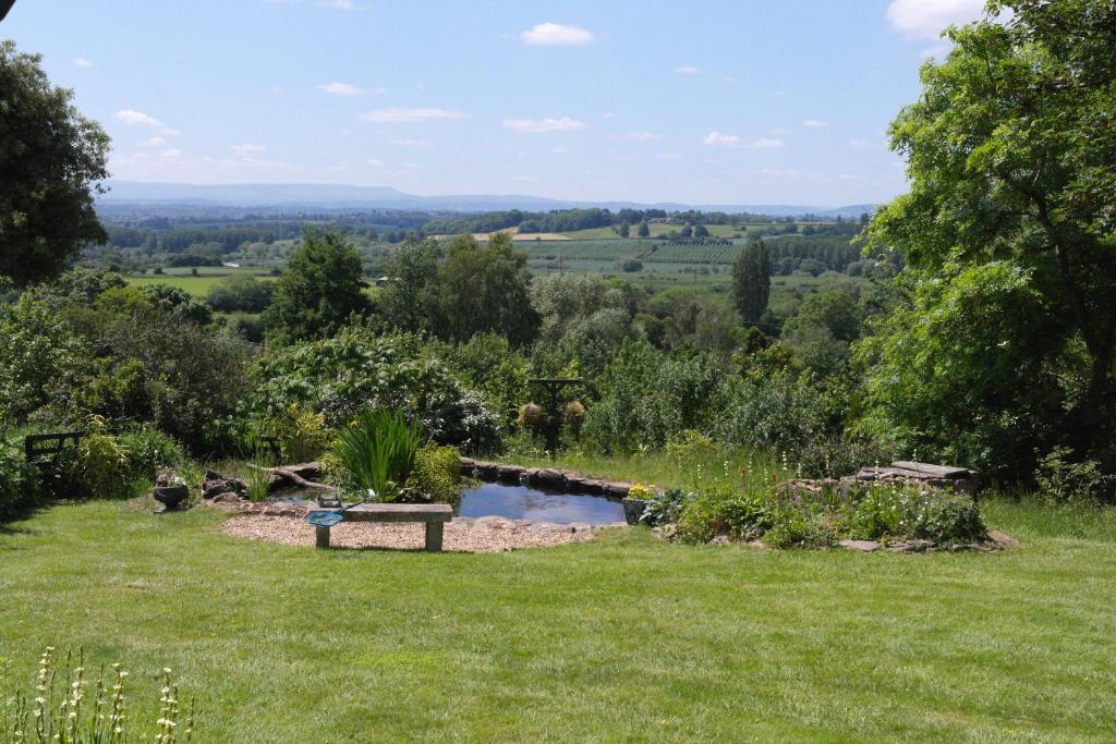 赫里福德Prospect BARN的花园,草地上设有长凳,还有池塘