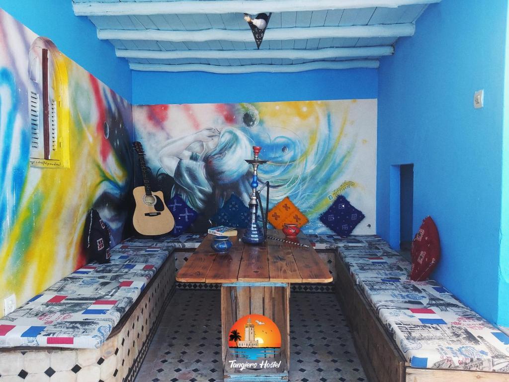 丹吉尔Tangiers Hostel的一间房间,墙上挂着一张桌子和一幅画