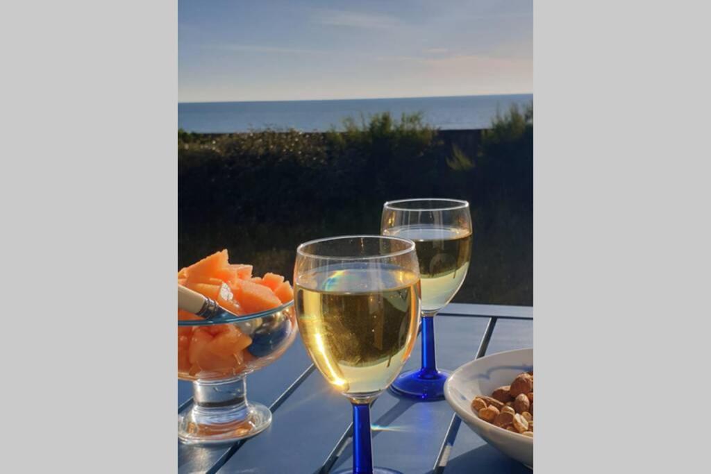 Hauteville-sur-MerVilla La Hautaise vue sur mer的两杯葡萄酒和一碗水果放在桌上