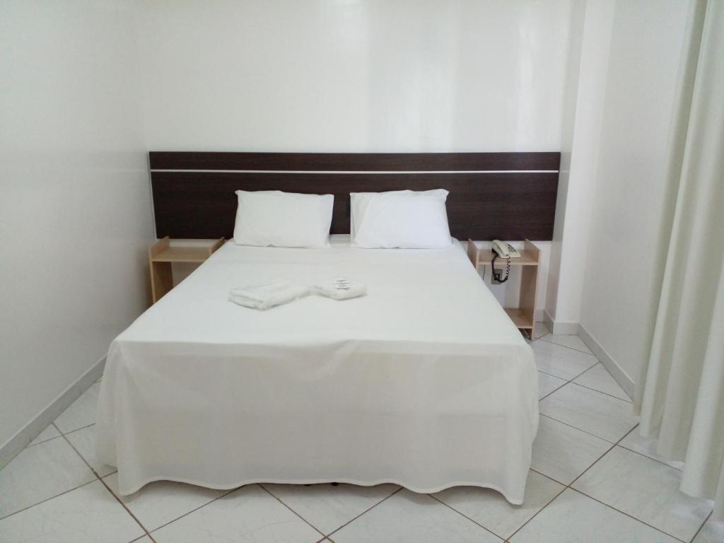 蒙蒂斯克拉鲁斯Hotel Minas Brasil的卧室配有白色的床单和枕头