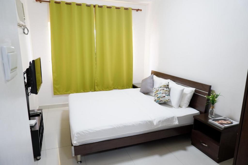 宿务Tancor Residential Suites的一间卧室配有一张带绿帘的床