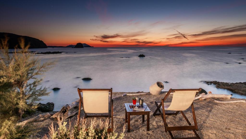 阿波罗尼亚塔尼亚米洛斯旅馆的日落时分海滩上的两把椅子和一张桌子