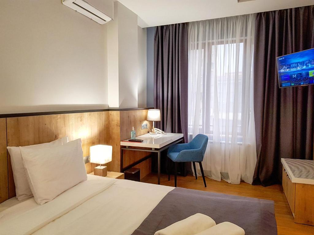 埃里温Hotel Alpha的配有一张床、一张书桌和一扇窗户的酒店客房